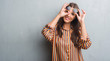 © Krakenimages.com - Young brunette woman over grunge grey wall wearing retro sunglasses and outfit with happy face smiling doing ok sign with hand on eye looking through fingers