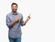 © Krakenimages.com - Adult hispanic man over isolated background smiling and looking at the camera pointing with two hands and fingers to the side.