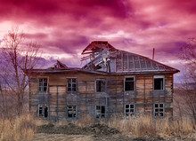 Old Ugly Dilapidated Wooden House On A Background Of Red Sky At Sunset