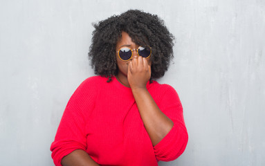 Sticker - Young african american plus size woman over grey grunge wall wearing retro sunglasses looking stressed and nervous with hands on mouth biting nails. Anxiety problem.