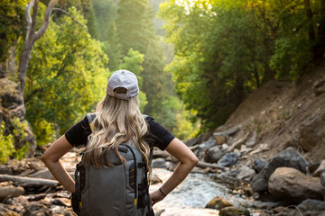 view from behind of a woman hiking near a mountain stream while on vacation.close up candid photo of