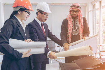 Arabic or western business people speaking about investments while meeting or discussing with Partner Business teamwork trust partnership group of Asian business people or engineers with blueprint.