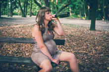Pregnant Woman Drinking Wine In The Park - Alcoholism Concept