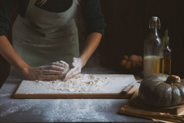 Women's hands knead the dough. Baking ingredients on wooden table