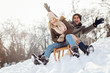 Two young people sliding on a sled 