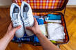 hands put sneakers to valise. packing for trip. travel concept
