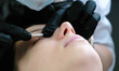 © familylifestyle - Cosmetologist's hands rubs the client's eyelids with a cotton swab. lash lamination. Side view.