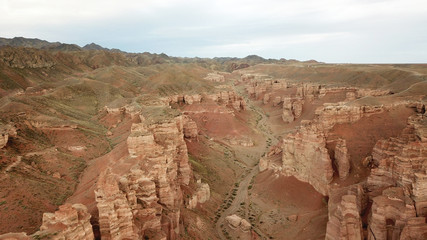 Charyn canyon. Grand canyon. Red sand and rocks. The sky in the clouds. Steep cliffs of the canyon. Shooting with the drone. Unusual footage. Clay rock canyon. Earth layers and different colors of roc