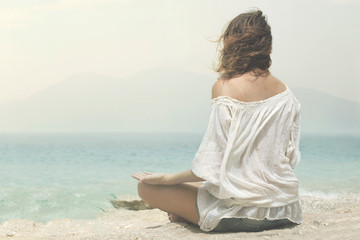 meditating woman does yoga exercises in front of the ocean