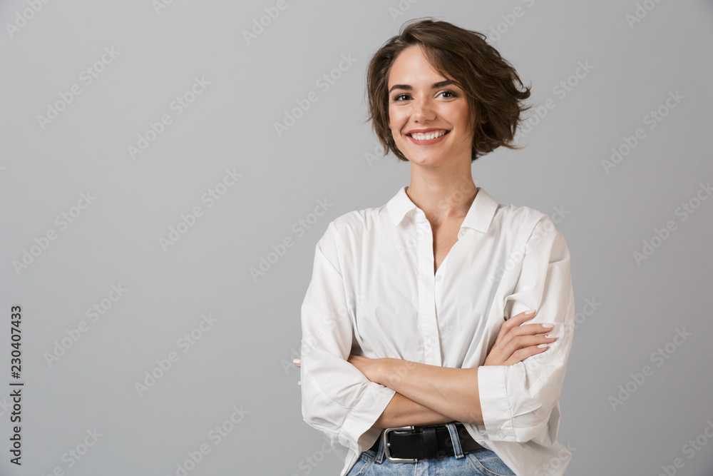 Happy young business woman posing isolated over grey wall background. - obrazy, fototapety, plakaty 