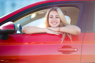 Photo of happy blonde sitting in red car with open window