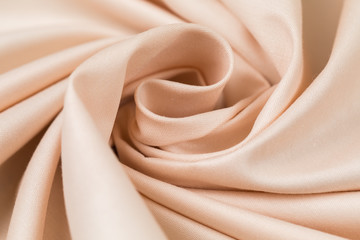 The monophonic fabric of beige color showing a beautiful drapery a spiral.