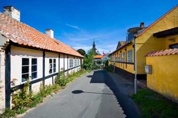 Wall Mural - Small colorful half-timbered houses in Gudhjem, Bornholm, Denmark. Church tower in the background.