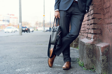 Wall Mural - Happy young formal dressed man leaning on a wall outdoors