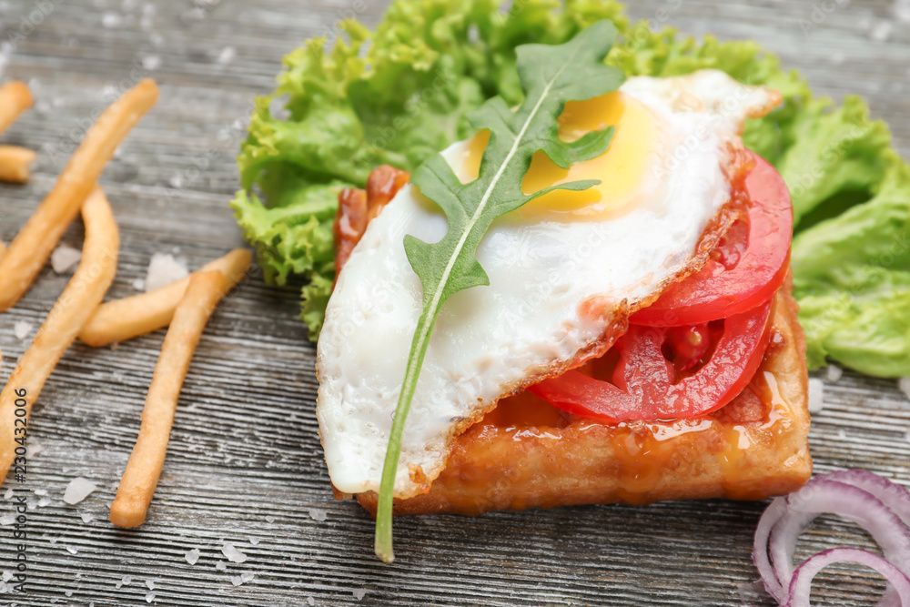 Delicious waffle with fried egg on wooden table