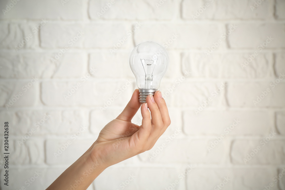 Female hand with eco light bulb on brick background