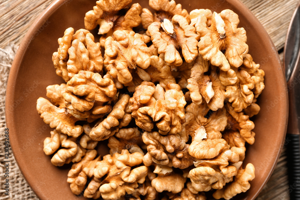 Plate with tasty walnuts on table, closeup