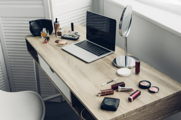 Wall Mural - close-up shot of workplace with laptop and makeup supplies at home