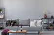 Industrial living room with simple grey sofa and metal furniture, real photo with copy space on the wall