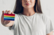 close-up shot of young transgender man holding card with pride flag on white