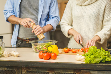 Lovely couple are talking and while cooking healthy food in kitchen at home. Close-Up.