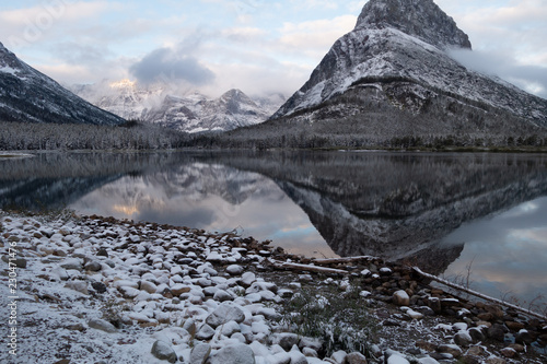 Fotografia, Obraz Mt Grinnell reflected in Swiftcurrent Lake in the early dawn light after a snow storm