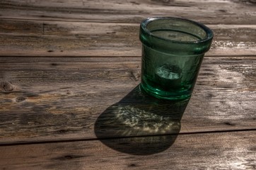Wall Mural - Glass in sunshine throwing coloured shadow on wooden table, Tuscany