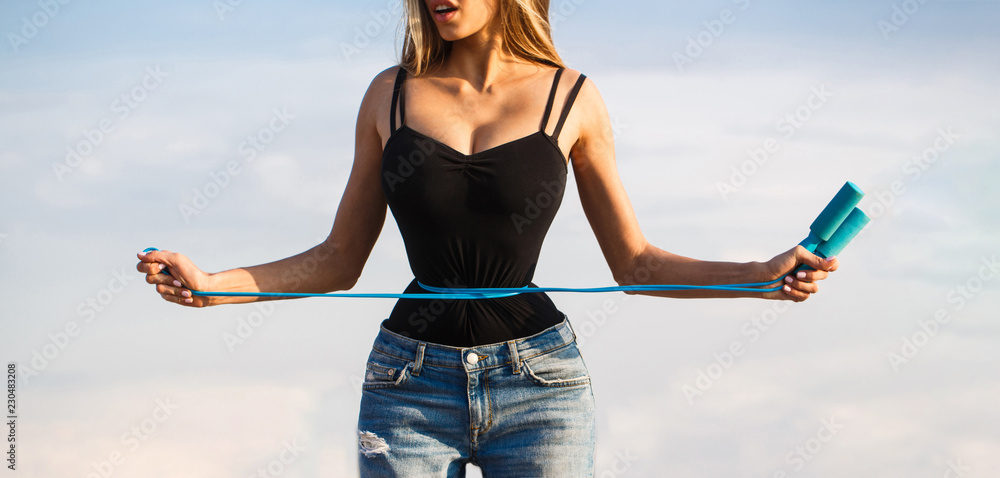 Fit fitness girl measuring her waistline with measure tape. Athletic slim woman measuring her waist by measure tape after diet. Slim body, jump rope. Girl with perfect waist with a jump rope in hands. - obrazy, fototapety, plakaty 