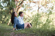 © soleg - young couple sitting on the grass in the forest and looking on sunset, summer nature, bright sunlight, shadows and green leaves, romantic feelings