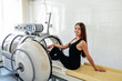 beautiful girl in a black T-shirt and white pants lies in a hyperbaric chamber