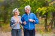 © lordn - Smiling senior active couple jogging together in the park