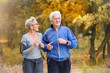 © lordn - Smiling senior active couple jogging together in the park