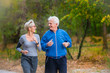 © lordn - Smiling senior active couple jogging together in the park