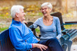© lordn - Smiling senior active couple sitting on the bench talking