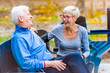© lordn - Smiling senior active couple sitting on the bench talking