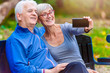 © lordn - Smiling senior couple in the park taking selfie