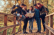 © Fxquadro - Group of young friends hiking in autumn colorful forest, looking at map and planning hike.