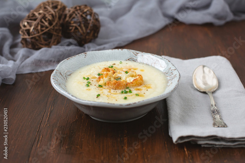 Fotografie, Obraz Creamy Cauliflower Soup topped with Brown Butter and Chives in a Rustic Setting