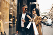 Shopping. Black Friday. Couple. Love. Man and woman with shopping bags and credit card are talking and smiling while walking down the street