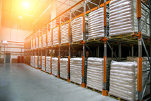 Hangar Warehouse With Rows Of Shelves With White Polyethylene Bags With Finished Factory Production