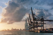 Cranes of the port of Miami and skyline of downtown Miami at sunset, in Florida, USA