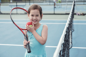 Young Asian girl tennis player on outdoor blue court