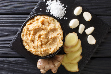 Poster - Raw spicy ginger garlic paste for asian cuisine close-up in a bowl on a black table. horizontal top view