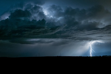 Wall Mural - a powerful branched lightningbolt strikes down from a severe thunderstorm in nebraska
