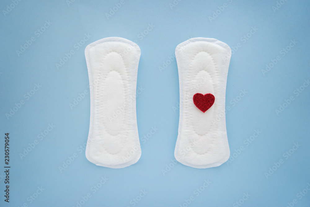 Menstrual pads with red heart on color background