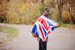 © AS Photo Family - African man in africa traditional shirt on autumn park with Great Britain flag.