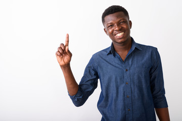 Wall Mural - Studio shot of young happy black African man smiling while point