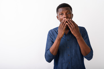 Wall Mural - Studio shot of young black African man looking shocked while cov