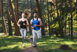 © proimagecontent - Young athletic couple wearing sportish clothes jogging in the sunny park, they listening music and enjoying of the good weather, healthy lifestyle and people concept