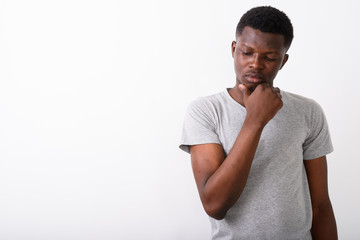 Wall Mural - Studio shot of young black African man thinking while looking sa